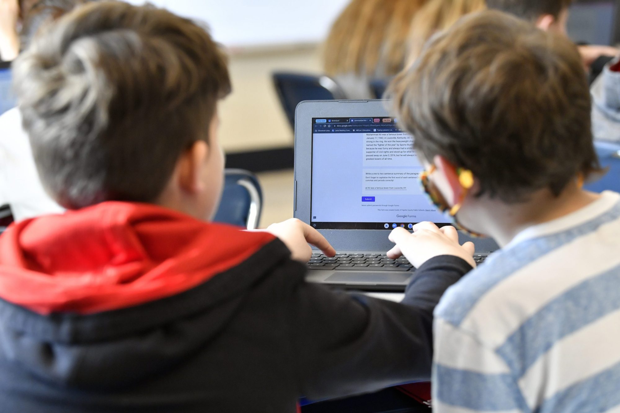 Two students work together on a laptop in class.