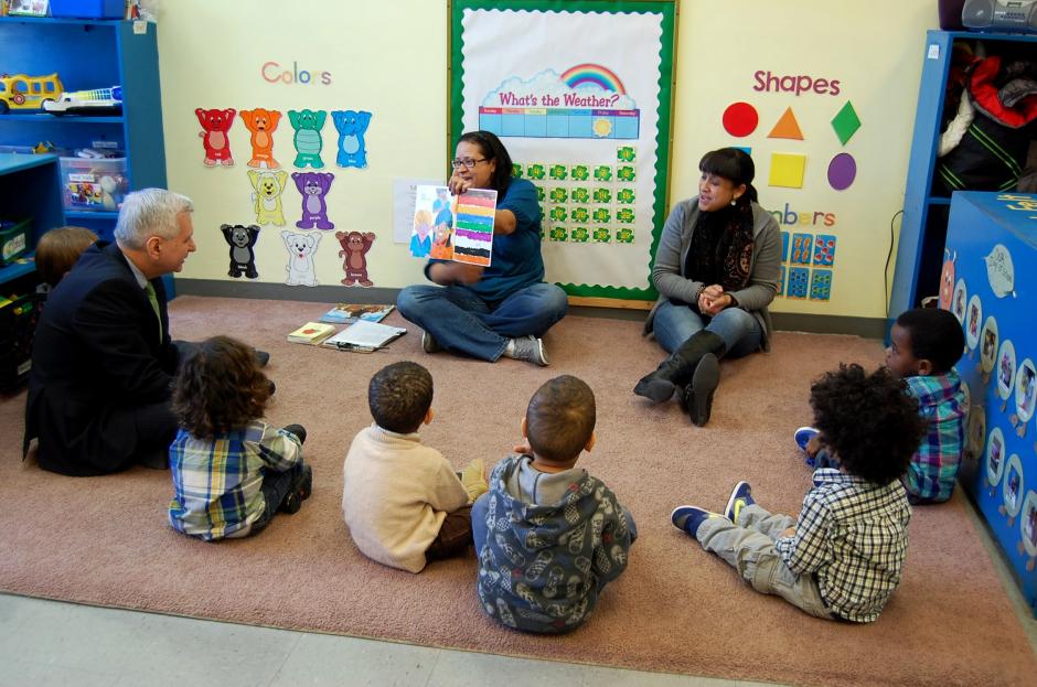 From the Senate floor to the preschool floor: Jack Reed (D-RI) sits crosslegged with the kids during a visit to Beautiful Beginnings in Providence, R.I. The pre-K center began in a shuttered strip- mall clothing store. Thanks to public and private funding, center is now located in a new light-drenched child-friendly facility.